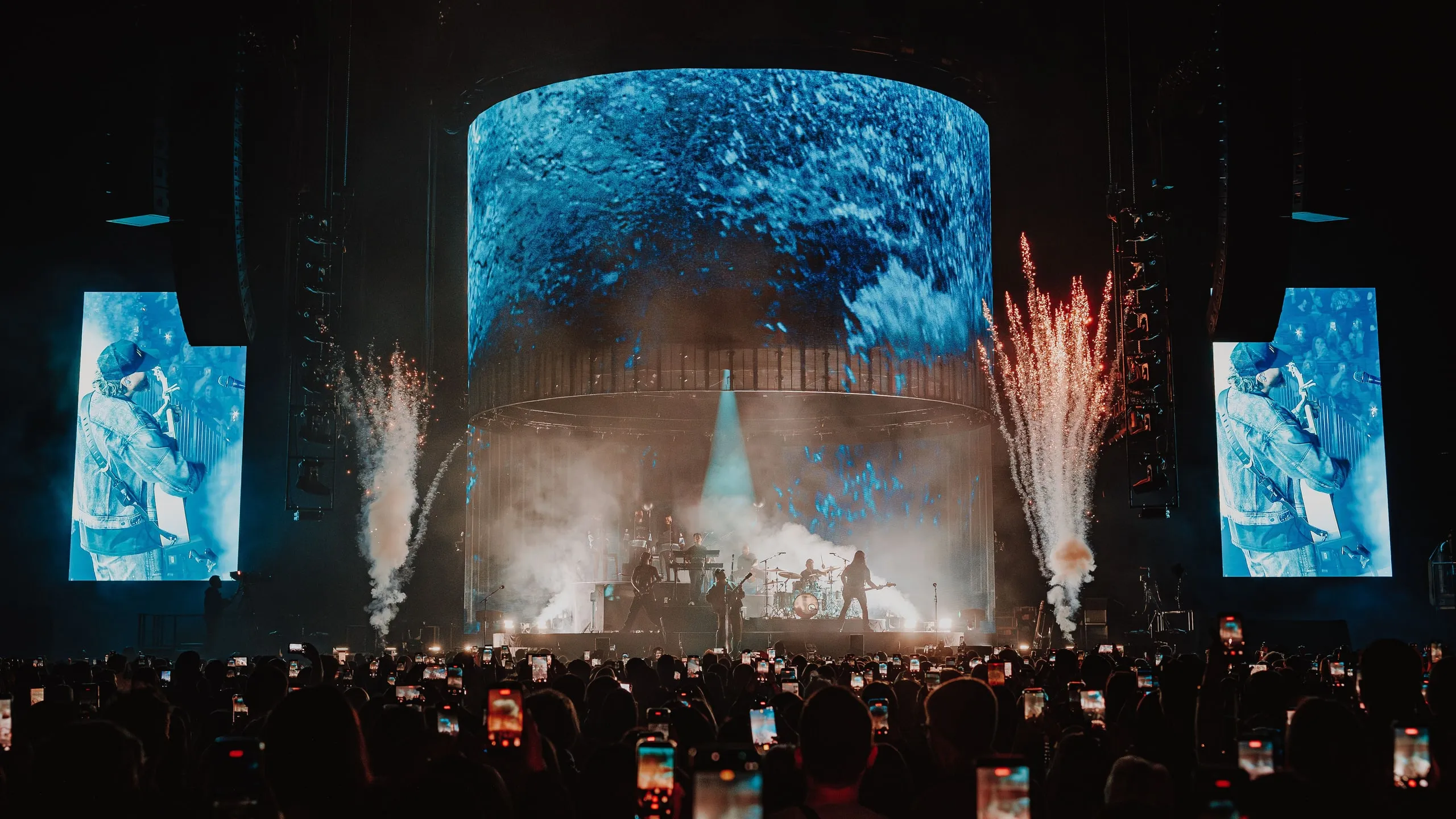Cylinder screen showing deep blue textured footage as fountain pyrotechnics fire either side of the stage