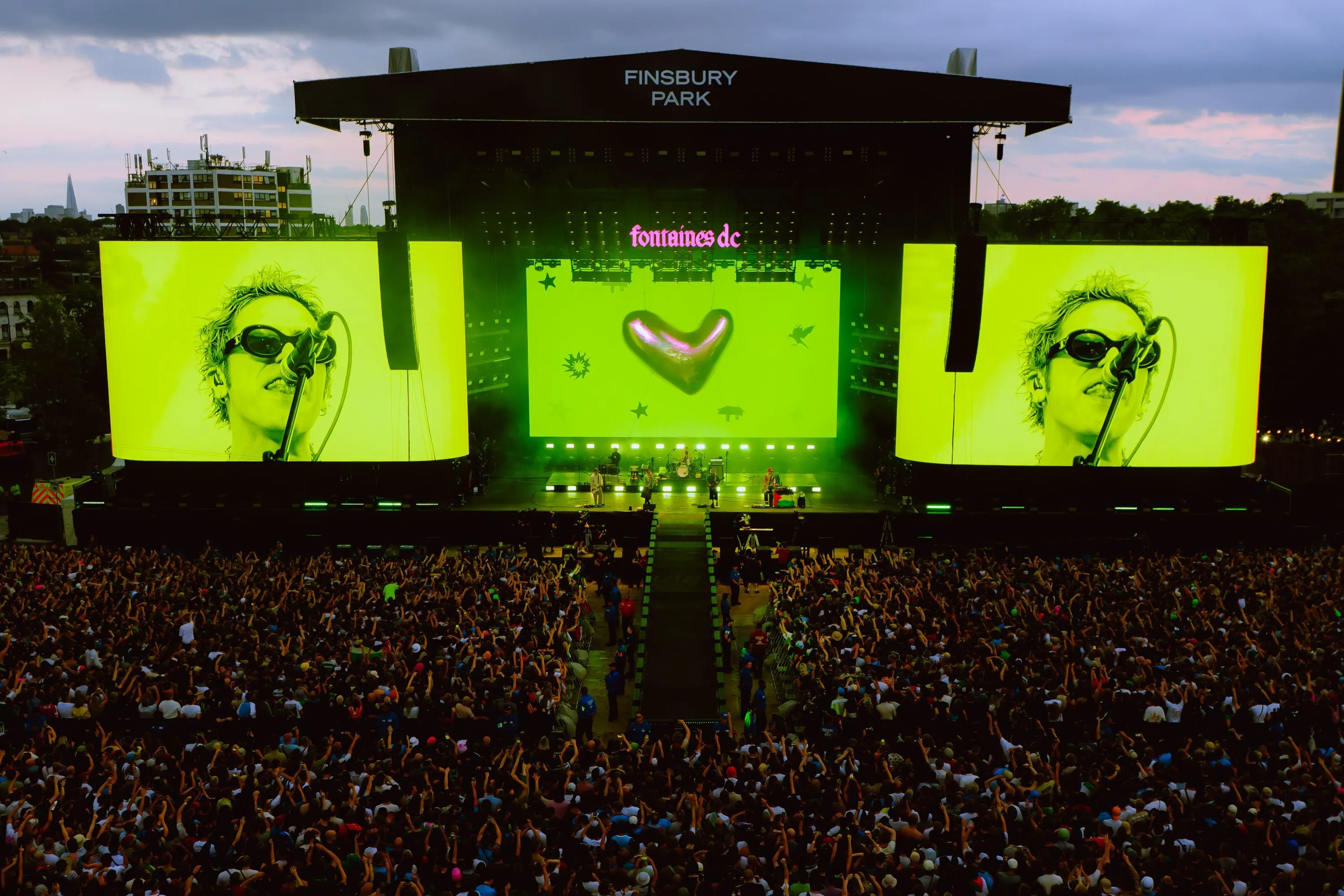 Fontaines DC on the main stage at Finsbury Park at dusk, with lime-green side screens, a heart on the centre LED wall and a packed crowd